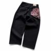 Back view of black wide leg jeans with pink cherry blossom embroidery across the right back pocket.