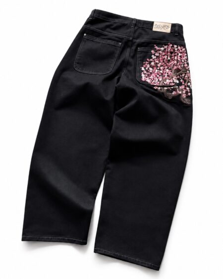 Back view of black wide leg jeans with pink cherry blossom embroidery across the right back pocket.