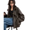 Model wearing a brown faux leather biker jacket with voluminous sleeves and blue jeans