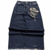 Back view of dark blue wide-leg jeans with skull-and-cap embroidery on the right pocket and embroidered waistband details.